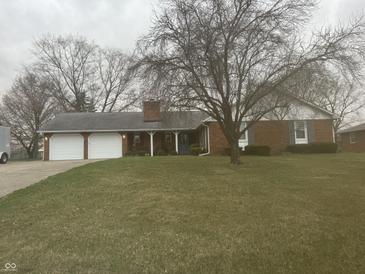 Charming brick home with attached two car garage and spacious front yard at 805 Stewart Rd, Anderson, IN 46012