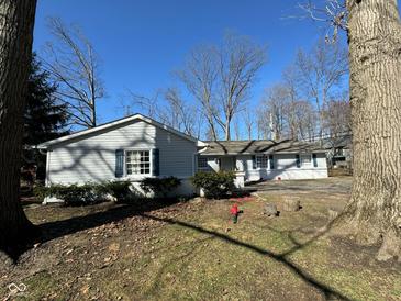 Charming single-story home with light siding, dark shutters, and mature trees at 1536 W 74Th Pl, Indianapolis, IN 46260