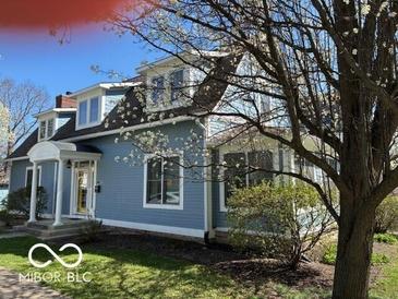Charming blue two-story home with a well-manicured lawn and blooming tree at 590 W Cedar St, Zionsville, IN 46077