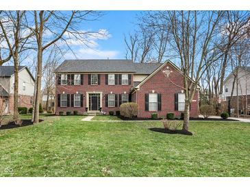 Traditional two-story red brick home featuring a lush front lawn, black shutters, and well-manicured landscaping at 6545 Briarwood Pl, Zionsville, IN 46077