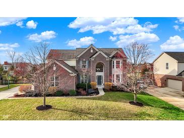 Beautiful two-story brick home with a manicured lawn and attractive landscaping on a sunny day at 9253 Windrift Way, Zionsville, IN 46077
