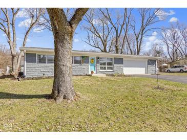 Charming single-story home with stone accents, a light blue door, and a well-manicured front lawn at 10427 N Delaware St, Carmel, IN 46280