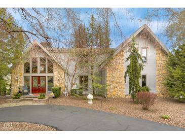 Beautiful home with stone and siding exterior, a red front door, and mature landscaping at 3849 Waycross Dr, Columbus, IN 47203
