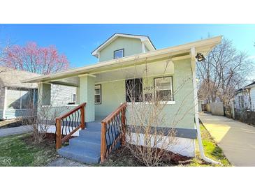 Charming home featuring a covered front porch, light green paint, and meticulous landscaping at 4929 Kingsley Dr, Indianapolis, IN 46205