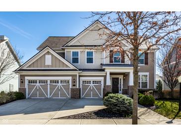Charming two-story home with a three-car garage and beautifully landscaped front yard under a bright blue sky at 12729 Brandenburg Dr, Carmel, IN 46032