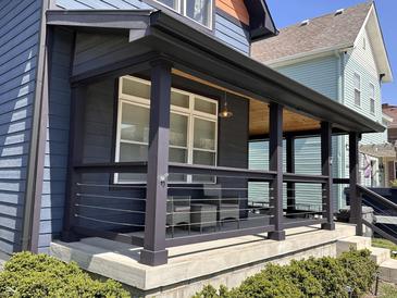 Inviting front porch features a seating area, modern railings, dark wood trim, and a wood ceiling at 1334 E Market St, Indianapolis, IN 46202