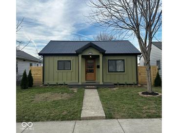 Charming home with a metal roof, wood fence, grassy yard, and welcoming walkway at 1716 E Kelly St, Indianapolis, IN 46203