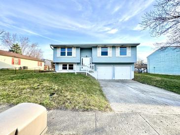 Charming light blue two-story home featuring a two-car garage, well-maintained lawn, and a welcoming front entrance at 5608 Lunsford Dr, Indianapolis, IN 46237