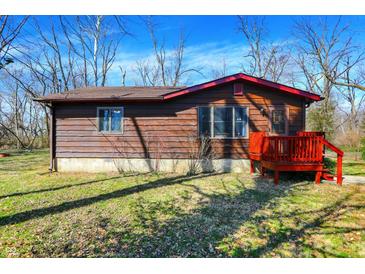 Charming single-story home with rustic wood siding and a red deck, nestled in a natural setting at 7916 W 275 N, Boggstown, IN 46110