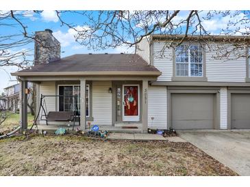 Charming two-story home with a red front door and a two-car garage nestled in a quiet neighborhood at 3051 Arrow Wood Ln, Indianapolis, IN 46214