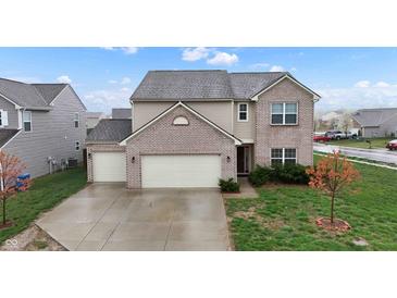 A charming two-story home boasts a three-car garage, brick accents, and beautiful landscaping at 7517 Heben Dr, Indianapolis, IN 46113