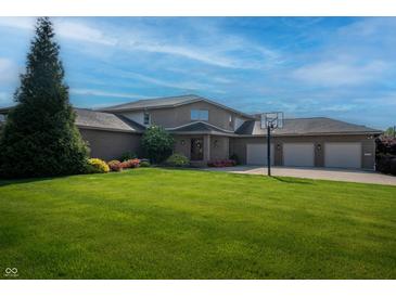 Spacious brick home with a three-car garage, lush green lawn, and basketball hoop in a suburban setting at 9398 W Mirror Rd, Columbus, IN 47201