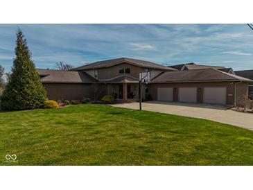 Beautiful brick home with a well-manicured lawn and three-car garage at 9398 W Mirror Rd, Columbus, IN 47201