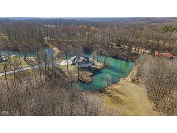 Idyllic aerial view of a stone home surrounded by tranquil water and mature trees in a peaceful, secluded setting at 2437 W Wavelyn N Cir, Martinsville, IN 46151