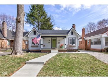 Charming cottage-style home featuring a manicured lawn, inviting walkway, and a cozy front porch with an American flag at 5937 Guilford Ave, Indianapolis, IN 46220