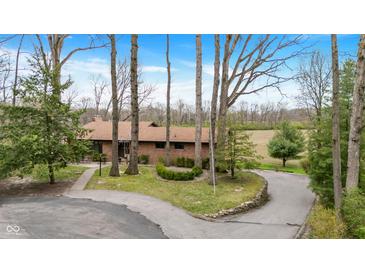 Traditional brick home boasts a circular driveway and beautifully landscaped front yard with mature trees at 4935 W Carriage Dr, New Palestine, IN 46163