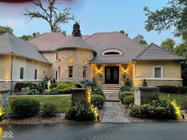Stunning stone and stucco home with a turret entry, beautiful landscaping, and a paver walkway at 10821 Club Point Dr, Fishers, IN 46037