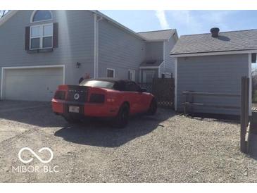 Exterior shot of home showing two-car garage, gravel driveway, and red convertible at 3036 Chase St, Indianapolis, IN 46217