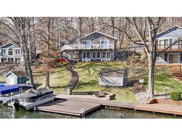 Lakefront home boasts multiple decks, a lakeside dock, and mature trees surrounding manicured lawn at 6290 Grouse Dr, Nineveh, IN 46164