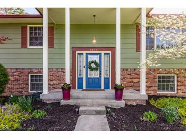 Close up on the front entry, featuring a bright blue door and lovely flowers at 7859 N Chester Ave, Indianapolis, IN 46240