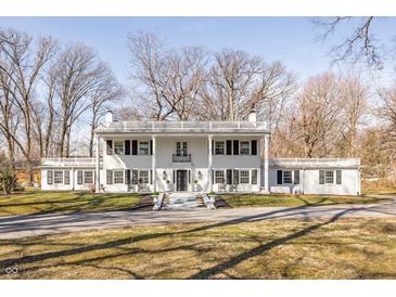 Stately two-story white home featuring classic architectural details and a large front yard with a circular driveway at 8020 N Meridian N St, Indianapolis, IN 46260