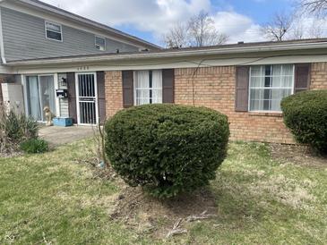 Charming brick and vinyl exterior featuring mature shrubbery, a security door and concrete patio at 6808 Summer Time Dr, Indianapolis, IN 46226