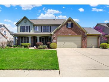 Charming two-story home with a well-manicured lawn and a three car garage at 7233 Capel Dr, Indianapolis, IN 46259