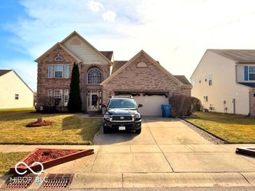 Charming two-story brick home featuring a manicured lawn and attached two-car garage at 1407 Aggie Ln, Indianapolis, IN 46260