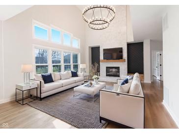 Bright living room featuring high ceilings, large windows, fireplace, and modern chandelier at 1351 Sullivans Rdg, Zionsville, IN 46077