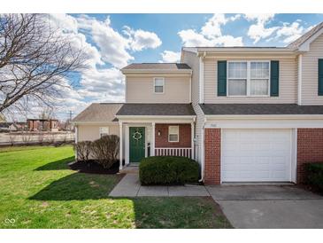 Charming townhome with a well-maintained lawn, attached garage, and inviting front porch with green door at 1568 Brookfield Cir, Franklin, IN 46131