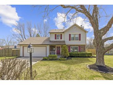 Charming two-story home featuring a well-manicured lawn, attached garage, and inviting red door at 12161 Pebblebrooke Ct, Indianapolis, IN 46236
