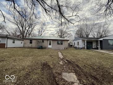 A single-story house with an expansive front yard and trees is pictured on an overcast day at 3812 S Ebright St, Muncie, IN 47302