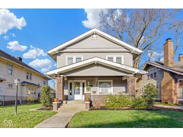 Charming two-story home featuring a welcoming front porch with brick pillars and lush landscaping at 3960 N Park Ave, Indianapolis, IN 46205