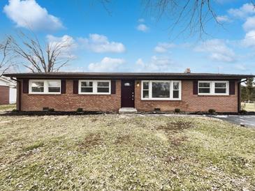 Charming brick ranch-style home with a well-manicured lawn and mature trees, under a bright blue sky at 7224 Rose Dr, Indianapolis, IN 46227