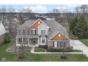 Stunning two-story home boasts brick, stone, and cedar accents, plus a perfectly manicured front yard at 10580 Saddlestone Dr, Fishers, IN 46040