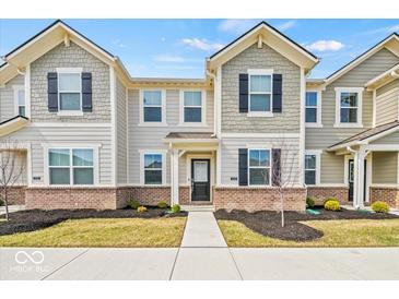Charming two-story townhome featuring a brick facade and neutral siding, complemented by black shutters and well-maintained landscaping at 17293 Rancorn Pl, Westfield, IN 46074