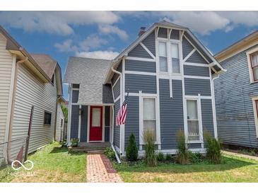 Charming home featuring stylish gray siding, crisp white trim, red door, and an American flag at 325 E 10Th St, Indianapolis, IN 46202