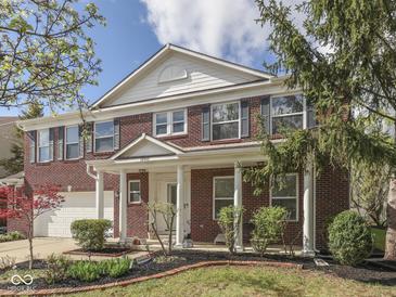 Charming red brick home featuring a welcoming front porch with white columns and a beautifully landscaped front yard at 10343 Waveland Cir, Fishers, IN 46038