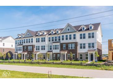 Attractive townhome complex with brick and siding, accented by green grass, trees, and a rustic wood fence at 14539 Hanford Ln, Carmel, IN 46032