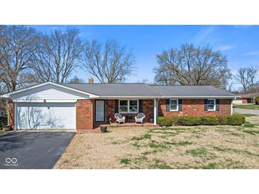 Charming brick home featuring an attached garage and inviting front porch at 5240 Magnolia Dr, Columbus, IN 47203