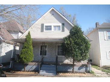 Charming house featuring a cozy front porch and meticulously landscaped yard with vibrant evergreens at 657 Birch Ave, Indianapolis, IN 46221