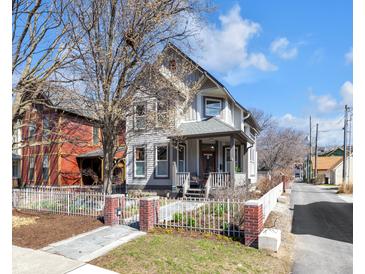 Charming two-story home with a fenced yard and inviting front porch at 827 N Park Ave, Indianapolis, IN 46202