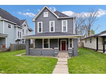 Charming two-story home boasts a freshly cut lawn and a welcoming red door at 2748 Carrollton Ave, Indianapolis, IN 46205