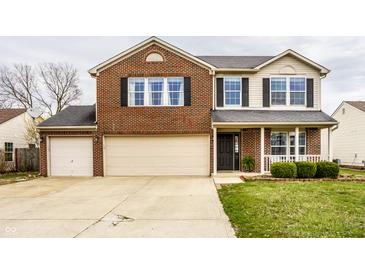 Inviting two-story brick home featuring an attached two-car garage and well-manicured front lawn at 305 Beacon Point Ln, Fortville, IN 46040