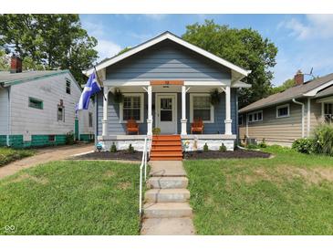 Charming blue home featuring a cozy front porch with seating and a well-maintained yard at 112 S Spencer Ave, Indianapolis, IN 46219