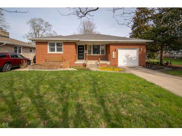 Charming brick home features a well-manicured lawn and attached garage, with inviting curb appeal at 1019 N Lesley Ave, Indianapolis, IN 46219