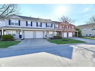 Inviting townhomes feature attached garages, lush landscaping, and charming curb appeal on a sunny day at 4951 Tuscany Ln, Indianapolis, IN 46254