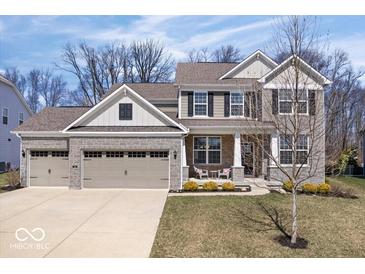 Charming two-story home boasts a manicured lawn, stone accents, and attached two car garage at 5658 Pecan Ct, Noblesville, IN 46062