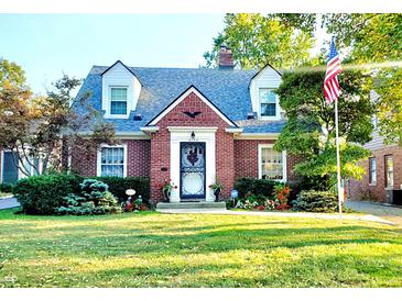 Charming brick home featuring dormer windows, manicured lawn, American flag, and inviting curb appeal at 6105 E St Joseph St, Indianapolis, IN 46219