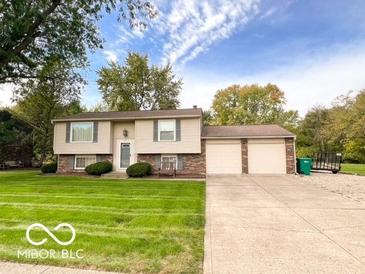 Split level home features a large manicured lawn, mature trees, and an attached two-car garage at 1402 Hornaday Rd, Brownsburg, IN 46112